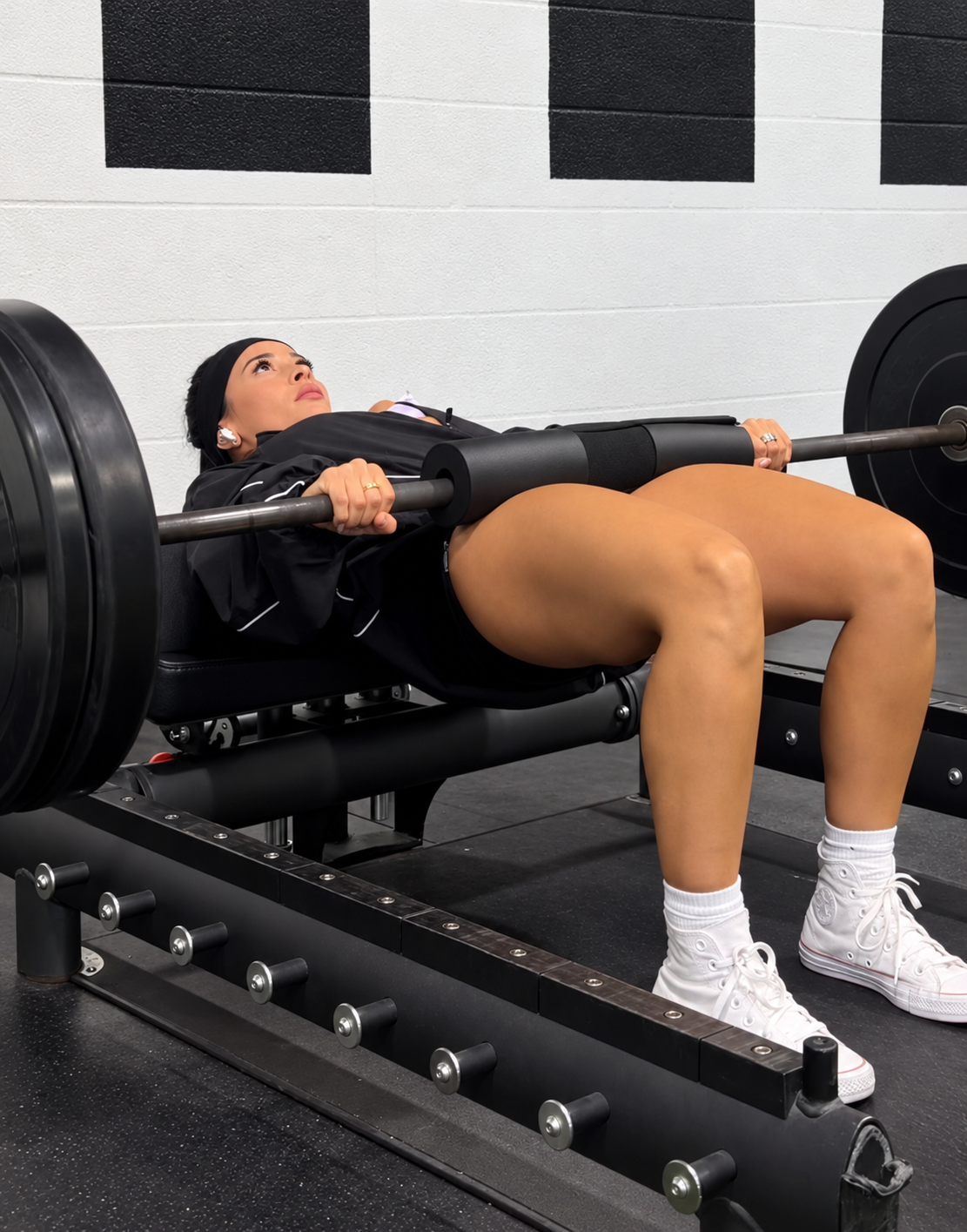 Ariana M. Thompson performing a loaded barbell hip thrust on a gym bench