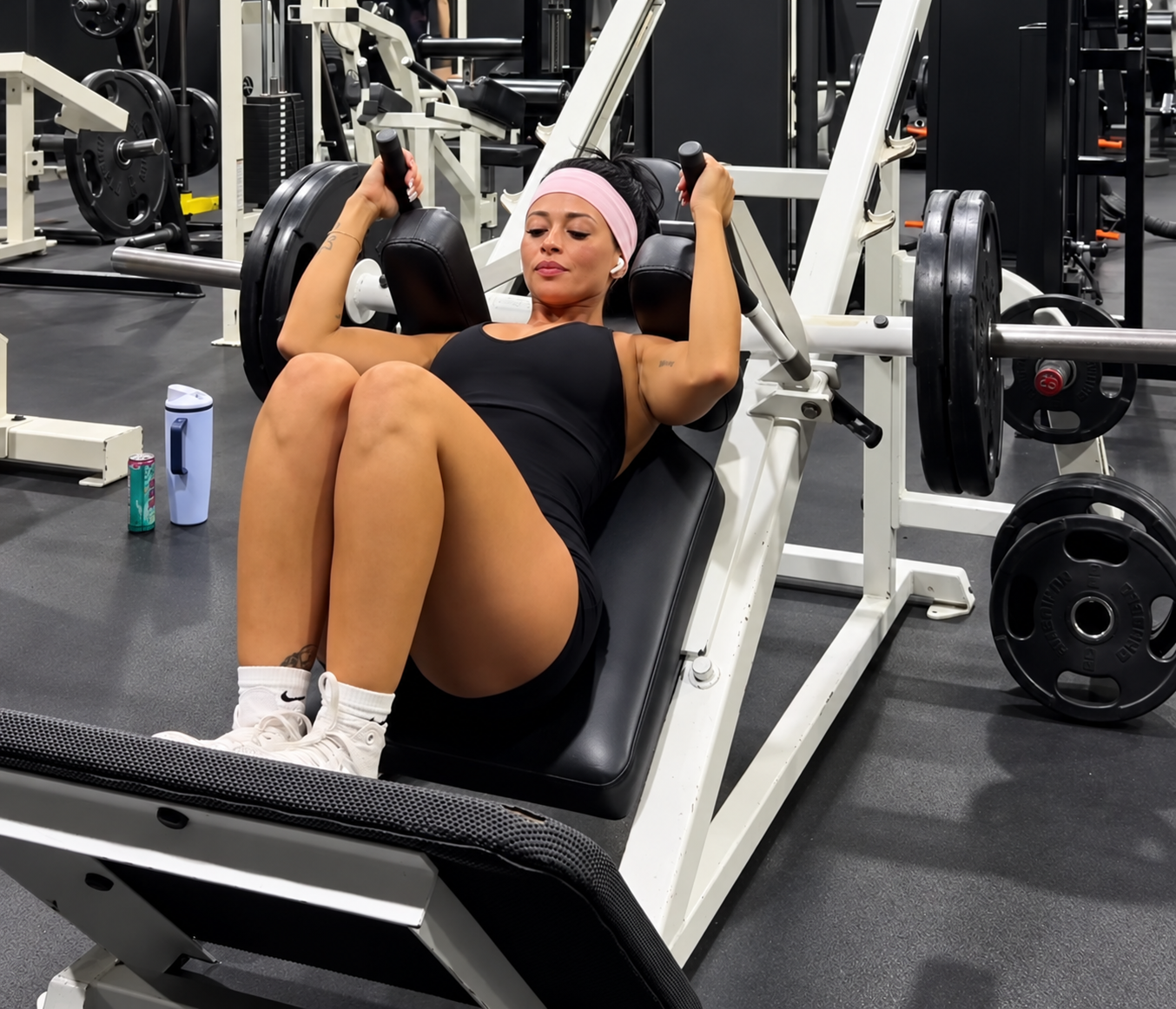 Ariana M. Thompson training on a plate-loaded leg press machine in the gym