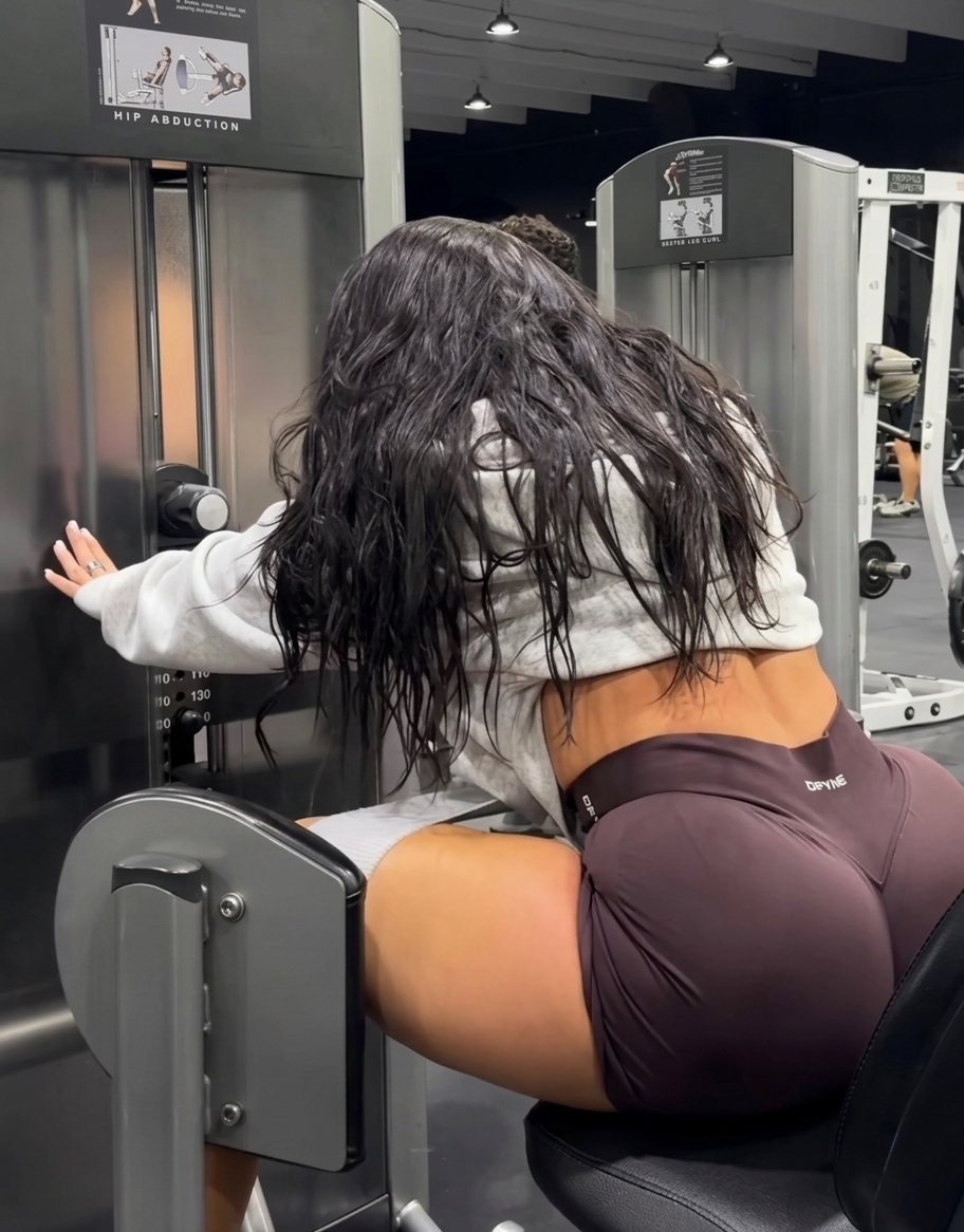 Ariana M. Thompson seated on a hip abduction machine in the gym