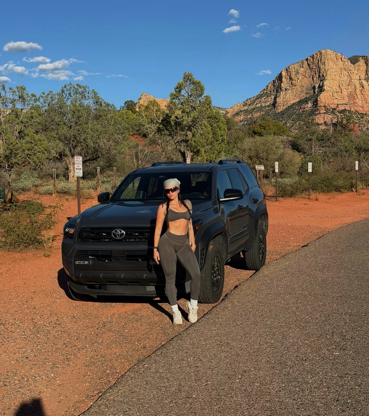 Ariana M. Thompson in gray athletic clothing beside an SUV with a red-rock landscape behind her