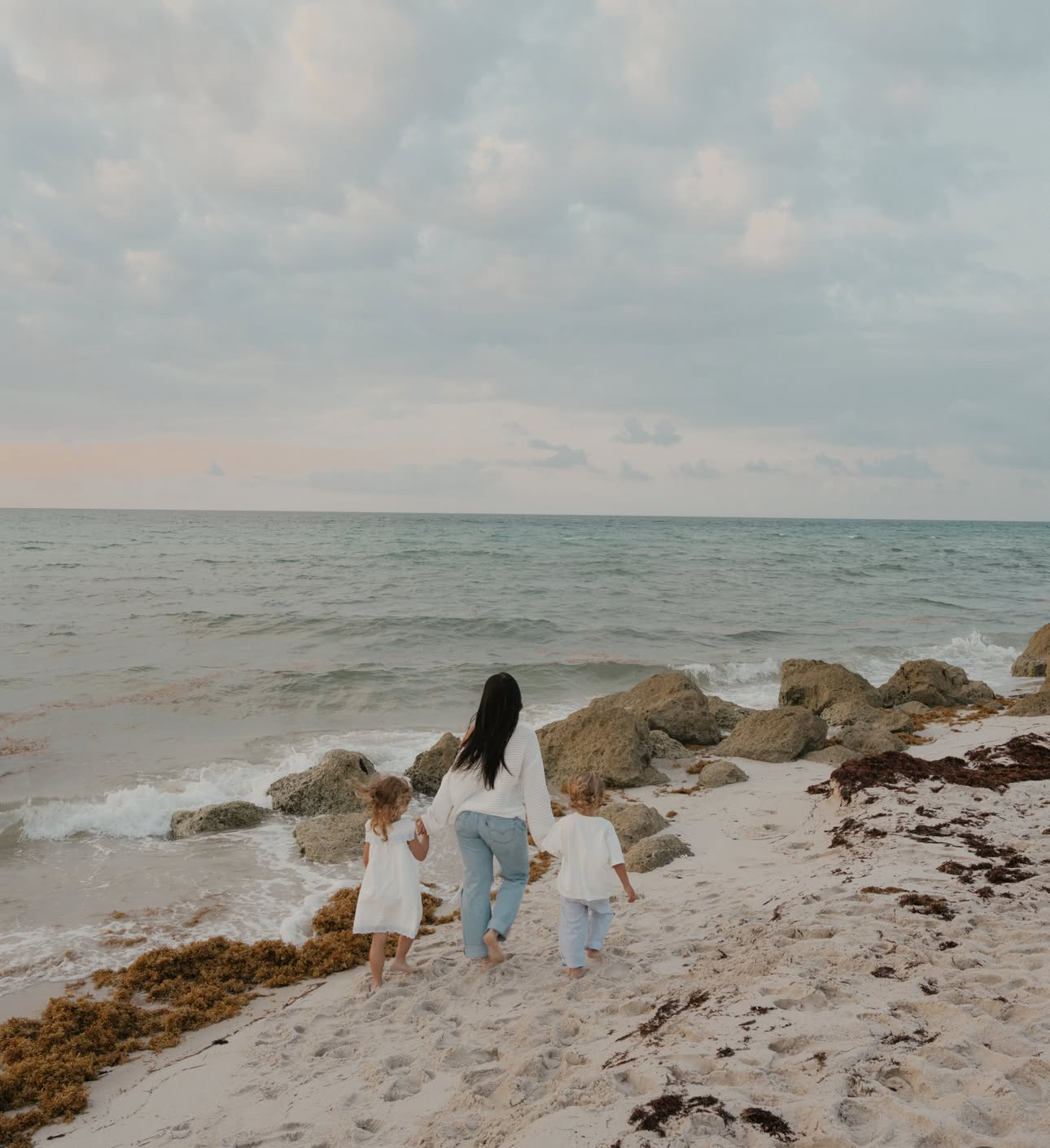 Ariana M. Thompson walking along the beach with her two children