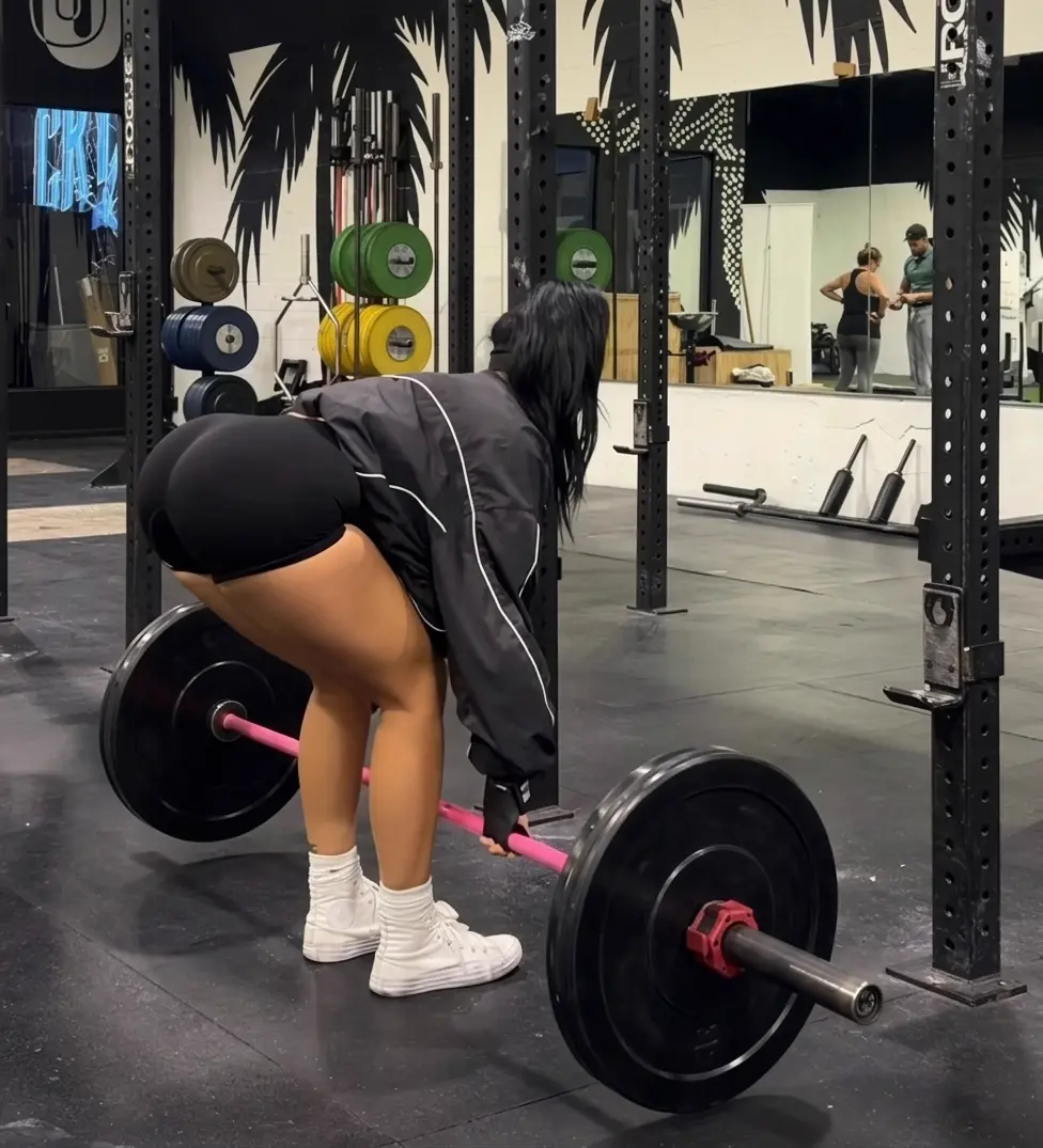 Ariana M. Thompson performing a Romanian deadlift with a loaded barbell in the gym